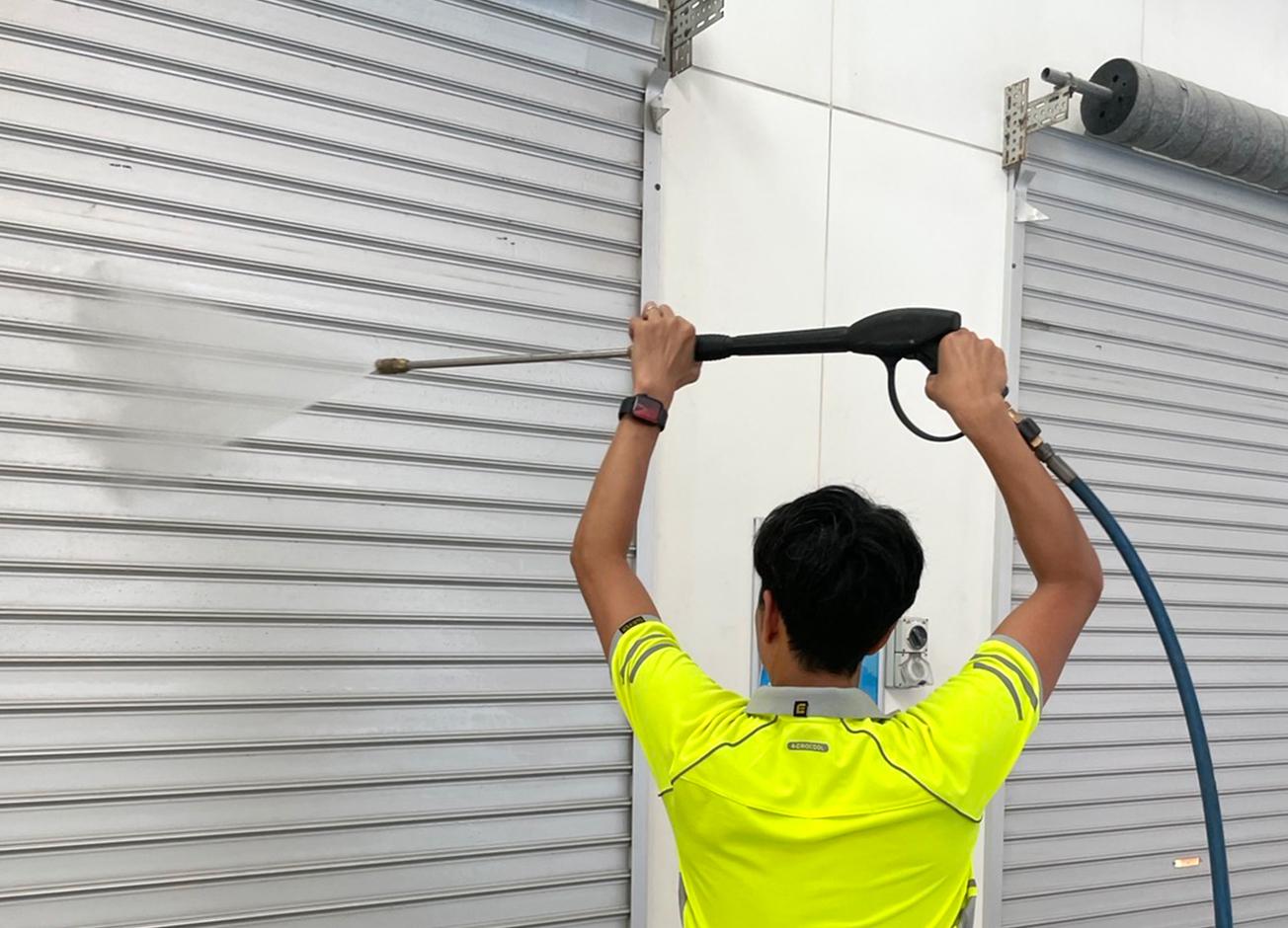 QCS Staff Cleaning Garage Door | Featured Image for the Commercial Pressure Cleaning Page of QCS Cleaning.